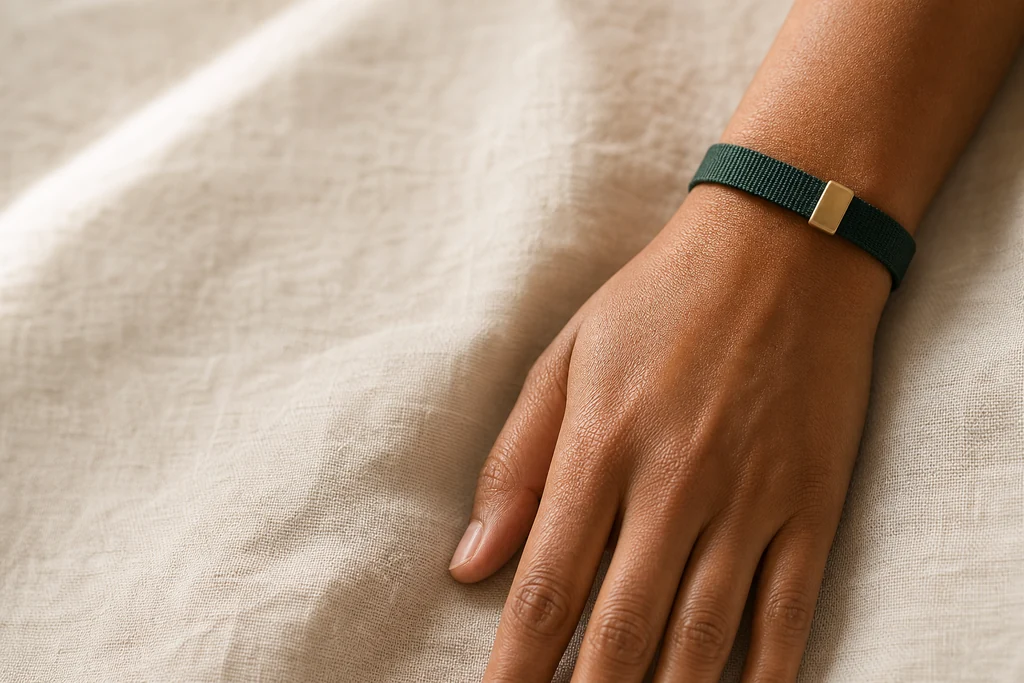 Pulso com uma pulseira lisa de tecido verde e fecho dourado, sem tela.